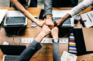 Team members fist bumping over a table with laptops