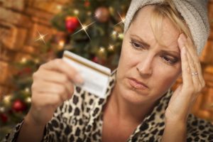 woman holding credit card with Christmas background, looking anxious