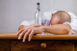 person passed out on a table with an empty bottle